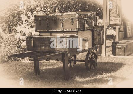 Sepia années 1940 vieux bagages d'époque empilés sur plateforme chariot chariot, gare d'époque, Severn Valley Heritage Railway, été Royaume-Uni. Banque D'Images