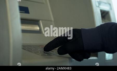 Main du Mans dans des gants insertion code PIN, voler de l'argent à partir du compte bancaire, atm Banque D'Images