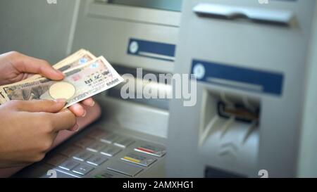 Femme obtenant japonais Yen de la machine de caissier automatique, retrait d'argent Banque D'Images