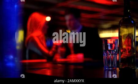 Couple rencontre d'abord dans la discothèque, les deux boissons à boire, fond flou Banque D'Images