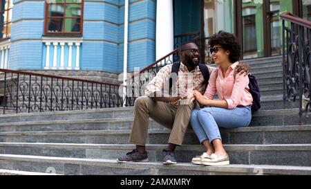 Les étudiants s'embrassent, assis sur les escaliers du bâtiment universitaire, l'amour des jeunes Banque D'Images