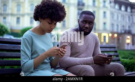 Gadget accro couple chat dans leurs smartphones, assis sur le banc, ignorer Banque D'Images