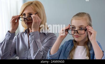 Femme blonde âgée et sa petite-fille mettant sur des lunettes et souriant, santé Banque D'Images