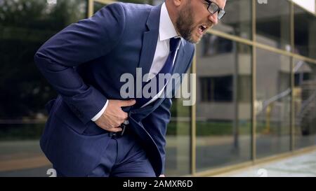 Travailleur en costume souffrant de maux d'estomac, de douleurs abdominales, de gastroentérite Banque D'Images