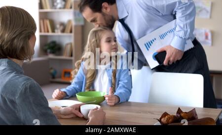 Père qui dit au revoir à la femme et embrassant petite fille qui va travailler, soins Banque D'Images