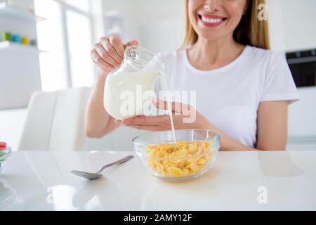 Photo recadrée de femme au foyer hands holding verser le lait frais savoureux petit-déjeuner de cuisson saine alimentation flocons de lumière blanche à l'intérieur cuisine concept Banque D'Images