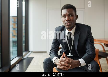 Portrait of African businessman sitting on chair usure formelle et à la caméra à at office Banque D'Images