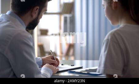 Thérapeute écrivant un reçu médical à une jeune femme patient, santé et traitement Banque D'Images