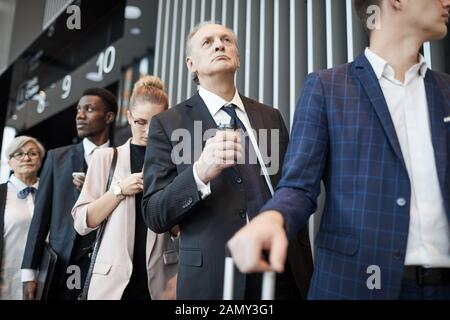 Senior man in suit holding tasse de café et d'attendre son tour sur l'enregistrement à l'aéroport. Banque D'Images