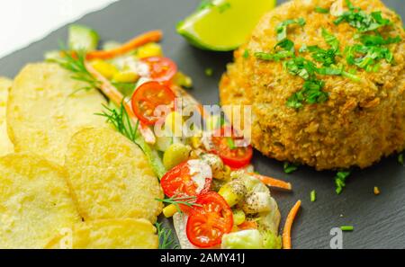 Fishcake haddock fumé avec des tranches de pommes frites et salade mixte, fruits de mer Banque D'Images