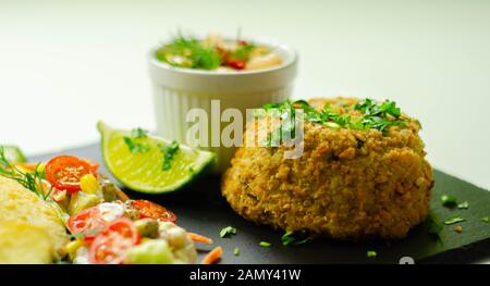 Fishcake haddock fumé avec des tranches de pommes frites et salade mixte, fruits de mer Banque D'Images