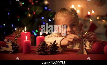 Fille souriante mettant étoile en bois sur arbre de noël fait à la main, célébration Banque D'Images