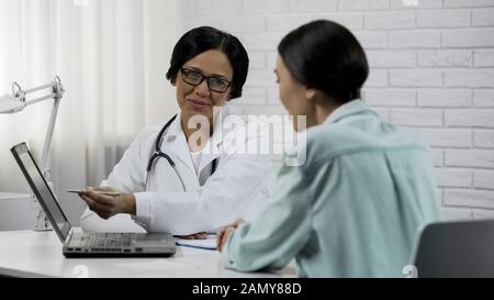 Médecin affichant les résultats du test sur l'ordinateur portable, traitement efficace, récupération du patient Banque D'Images