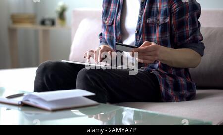 Homme entrant des données de carte de crédit dans la tablette, payant pour le billet d'avion, réservation Banque D'Images