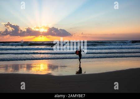 Silhouette de surfers sur la plage de la mer Méditerranée. Photographié à Tel Aviv au coucher du soleil Banque D'Images