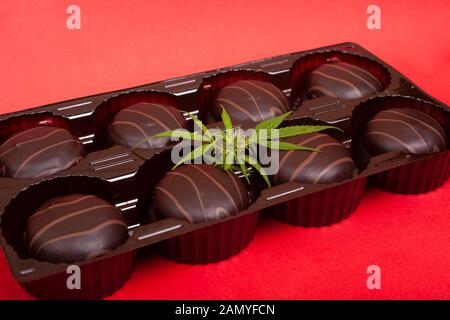 Les cookies au chocolat avec des guimauves et de la marijuana. le cannabis des cookies sur fond rouge. Banque D'Images