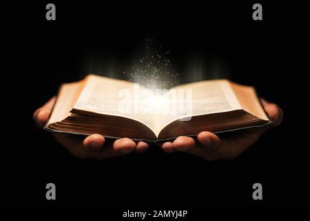 L'homme détient le livre Sainte de la bible sur fond noir Banque D'Images