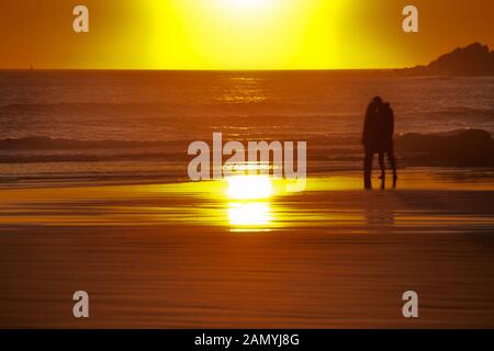 Couple kissing on Croyde Bay plage au coucher du soleil Banque D'Images