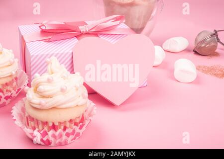 Amour saint valentin décoration crème cupcake et cadeaux coeurs sur fond rose avec copie espace pour le texte Banque D'Images