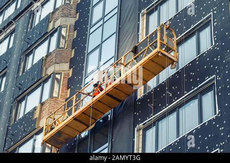 Construction suspendu berceau près de mur de hightower residentaial avec isolation du bâtiment et façade ventilée sur chantier de construction. Engineering Banque D'Images