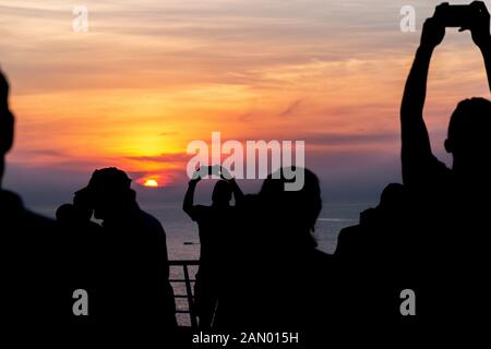 Les touristes en croisière holding up cellphones prendre des photos et vos autoportraits du lever du soleil au large des côtes de Cuba. Banque D'Images