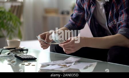 Homme calculant l'argent laissé au prochain salaire, pauvre mâle économisant son argent, finance Banque D'Images