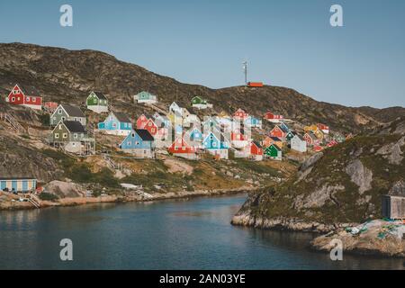 Des maisons colorées parsement les collines de la ville de pêcheurs de Kangaamiut, à l'ouest du Groenland. Icebergs du glacier de Kangia au Groenland nageant avec le ciel bleu Banque D'Images