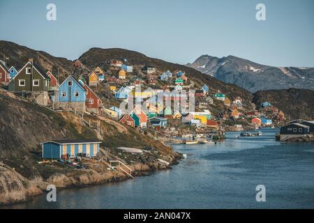 Des maisons colorées parsement les collines de la ville de pêcheurs de Kangaamiut, à l'ouest du Groenland. Icebergs du glacier de Kangia au Groenland nageant avec le ciel bleu Banque D'Images