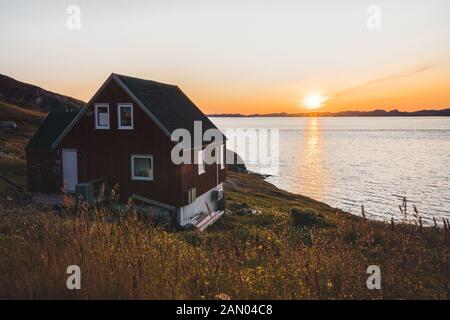 Maison typique de pêcheurs en bois coloré avec iceberg à Qeqertarsuaq, baie de Disko Groenland et Ilulissat. Architecture typique dans le cercle arctique. Banque D'Images