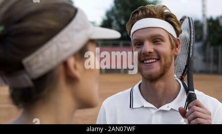 Une femelle flirtant avec un jeune beau joueur de tennis au court, homme souriant à la fille Banque D'Images