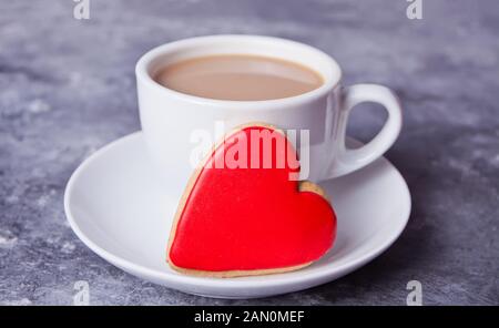 Tasse de café et un cœur rouge en forme de cookie sur la table gris Banque D'Images