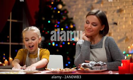 Mère regardant sa fille excitée préparer des biscuits pour le dîner de Noël Banque D'Images