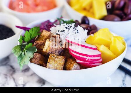 Végétalien sain bol bol Bouddha poke ou avec du riz basmati, mangue, tofu frit, violet chou, radis, olives kalamata, gingembre mariné et sesam noir Banque D'Images