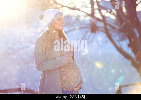 Bonne femme enceinte en plein air, belle future maman profitant de la belle journée enneigée d'hiver et lumière de soleil vive, l'amour de famille et le nouveau concept de vie Banque D'Images