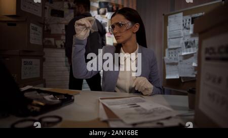 Scientifique médico-légale femme dans des gants examinant la puce de preuve, en trouvant la moindre idée Banque D'Images