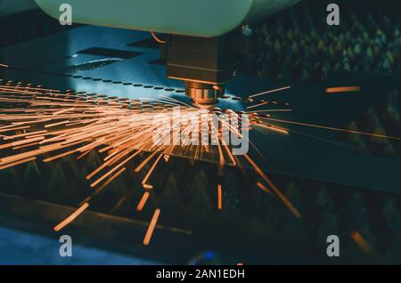 Machine pour la découpe laser de métal. Tête laser coupe la feuille avec un faisceau d'étincelles, de diffusion dans des directions différentes Banque D'Images