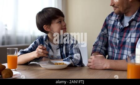 Mignon homme enfant se réjouissant savoureux petit déjeuner, fils et père ayant le petit déjeuner Banque D'Images