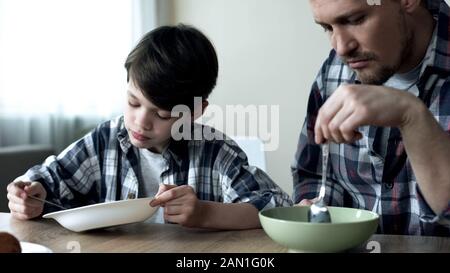 Le père et son fils qui mangeaient des cornflakes le matin, le petit déjeuner était médiocre Banque D'Images