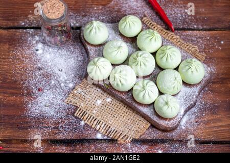Pâte gelée khinkali aux épinards. Garnie de Chili rouge, d'aneth et De Persil. Sur un fond en bois. Espace de copie. Banque D'Images