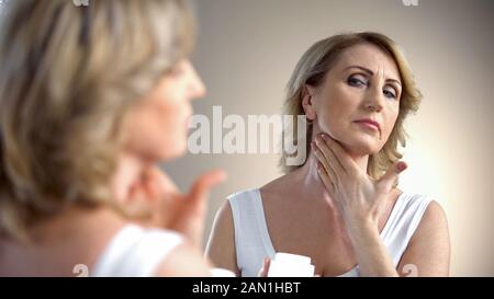 Femme âgée appliquant de la crème anti-âge sur le cou, soins de la peau dans la vieillesse, rides Banque D'Images