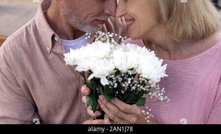 Happy senior couple nuzzling, holding Flowers bunch ensemble, date anniversaire Banque D'Images