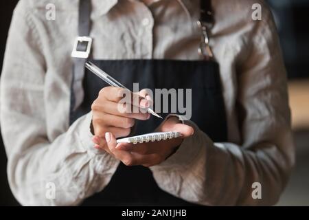 L'écriture de serveuse prend la commande au service du client dans le café Banque D'Images