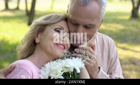 Happy elderly woman holding Flowers, caresser le visage, mâle mature l'amour, la romance Banque D'Images