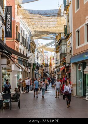 Les amateurs de shopping profitent du soleil de l'après-midi dans la rue commerçante colorée et piétonne de Séville, Calle Sierpes. Banque D'Images