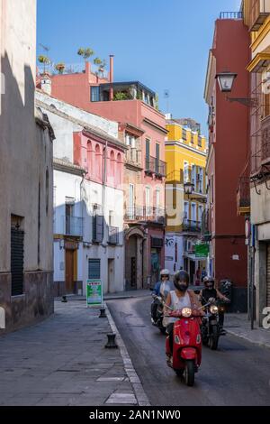 Scooters et moto passant par Iglesia de San Esteban dans la rue colorée San Esteban, Séville. Banque D'Images