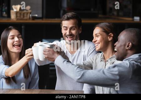 Des amis heureux et divers disent aux encouragements de s'amuser dans un café ensemble Banque D'Images