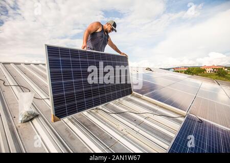 Un électricien installe des panneaux solaires sur le toit. Banque D'Images