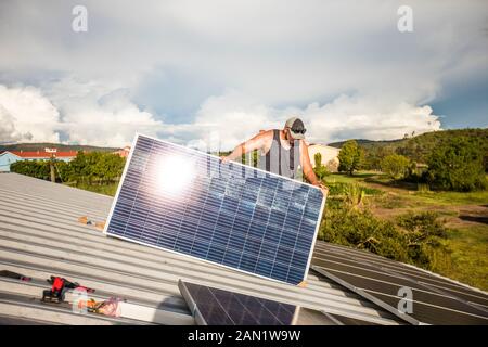 l'employé installe des panneaux solaires sur le dessus du bâtiment. Banque D'Images