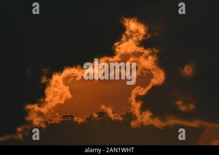 Nuages colorés alors que le soleil passe sous l'horizon, peignant la formation de nuages rétroéclairés avec une lueur rouge dans les régions rurales de l'Alberta Canada. Banque D'Images