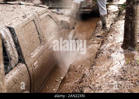 Voiture hors-route passant par les trous de boue profonde. Détail de voiture avec sale de boue rempli - carwash concept. roues. sale roue se dresse sur route forestière Banque D'Images